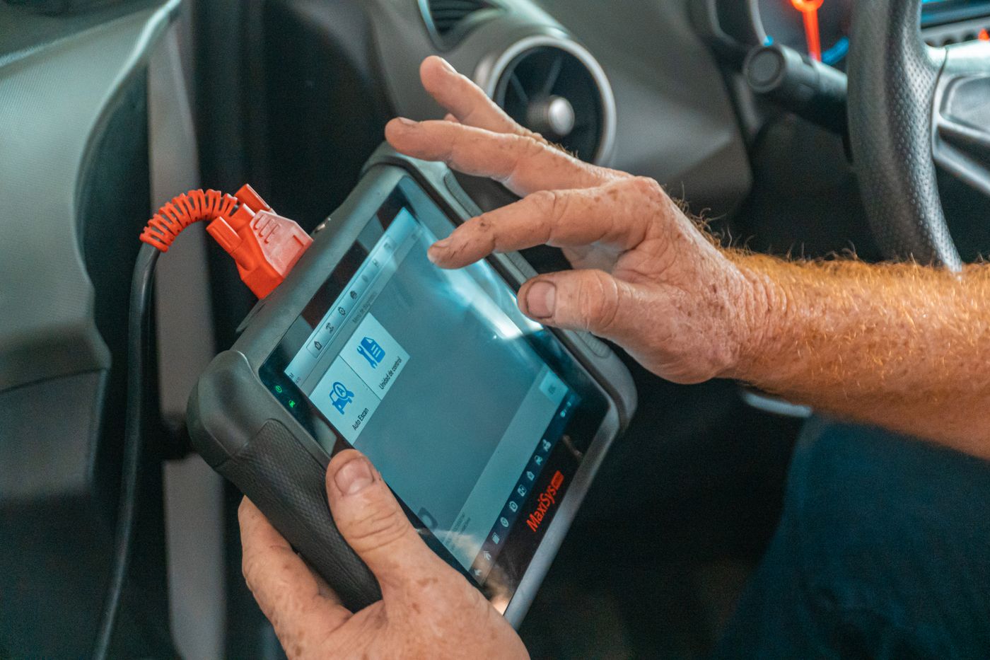 Meistras laiko diagnostikos planšetę, prijungtą prie automobilio